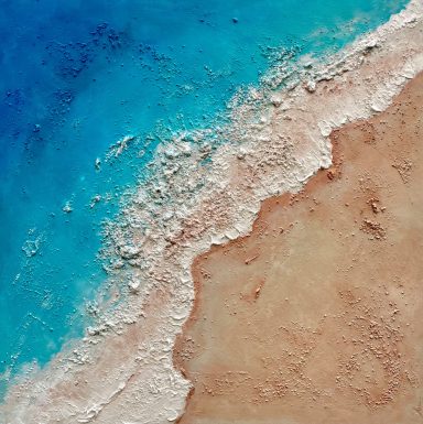 PLATJA Vista aérea de la costa, con agua azul y arena beige.